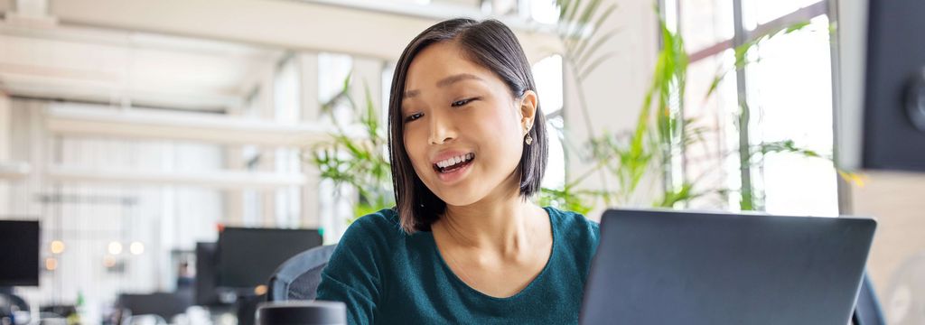 Asiatische Frau am Laptop spricht mit Alexa