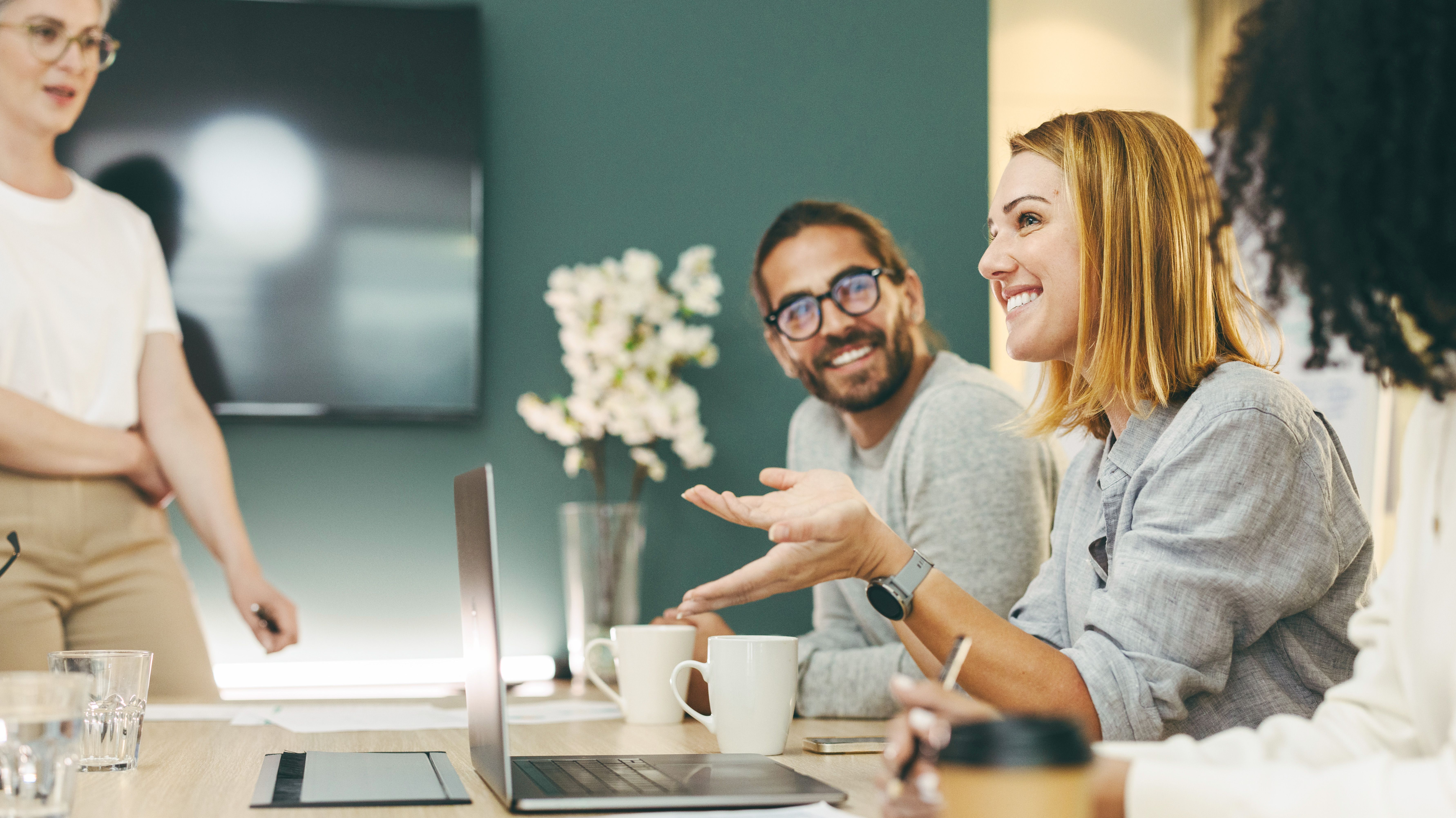 Vier zufriedene Personen an einem Schreibtisch im Gespräch