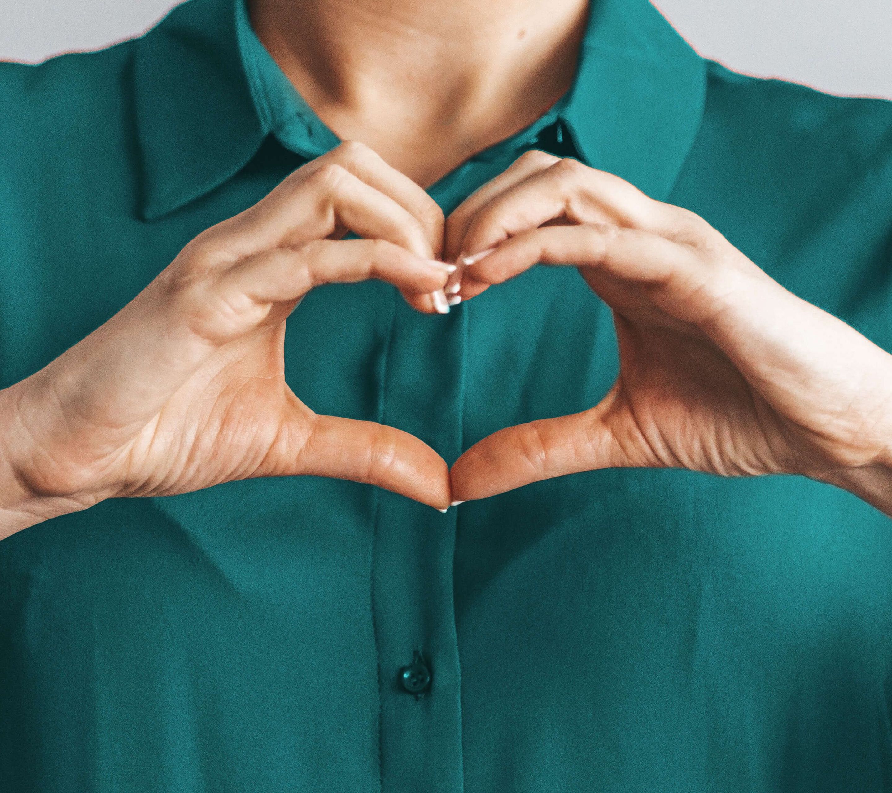 Woman with blouse makes a heart with her hands