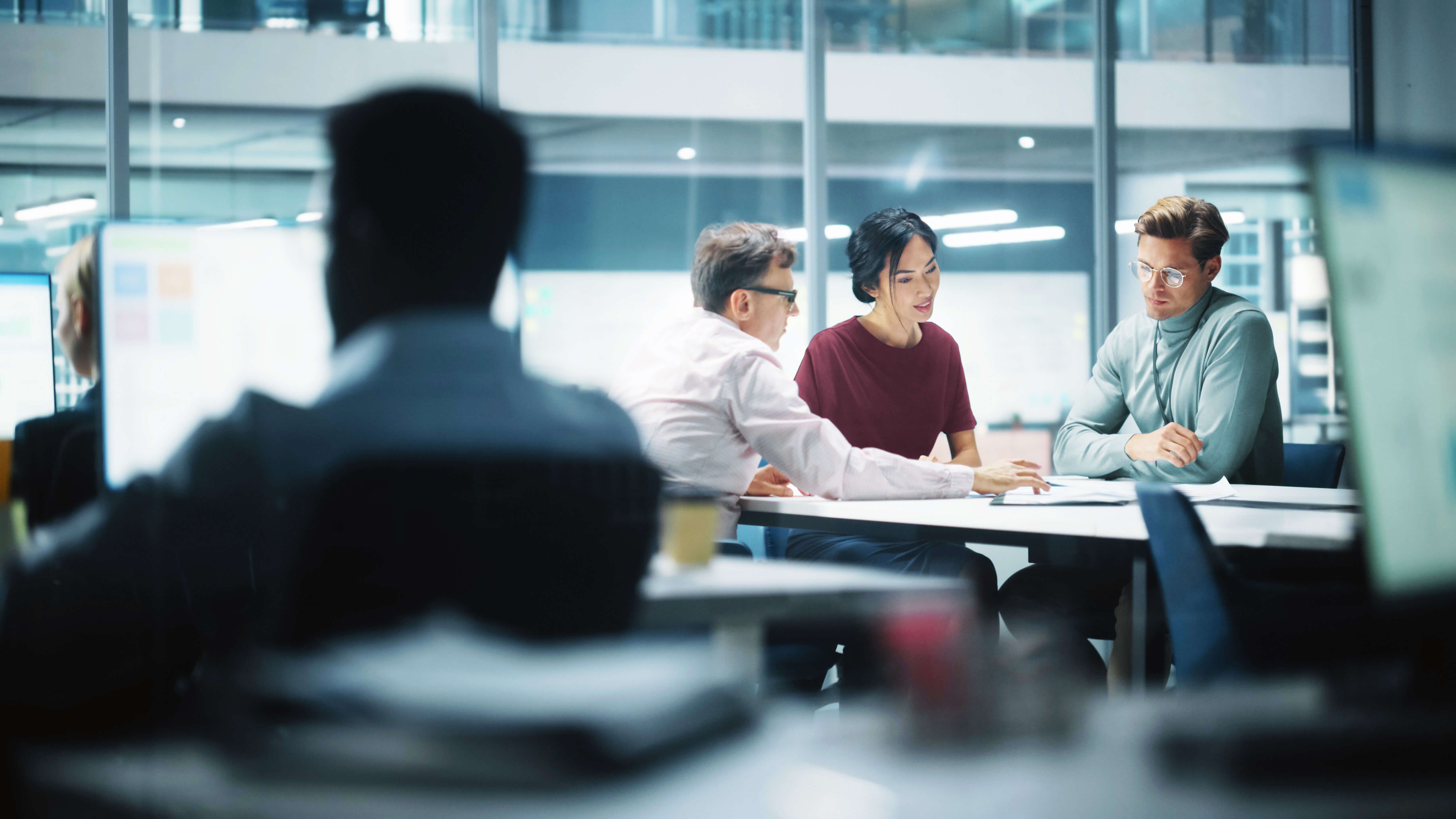 Zwei Männer und eine Frau an einem Tisch in einer Besprechung