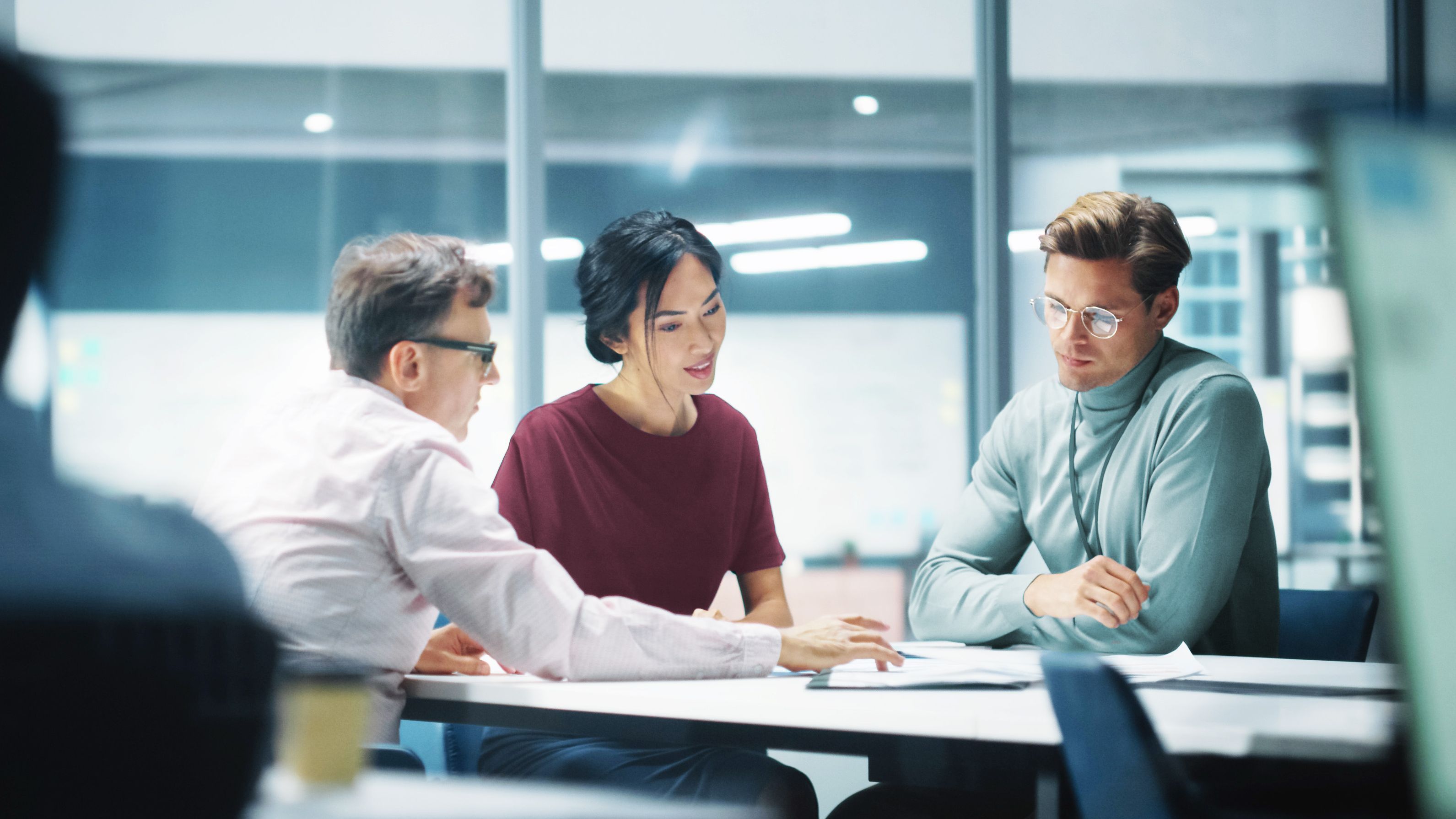 Zwei Männer und eine Frau an einem Tisch in einer Besprechung