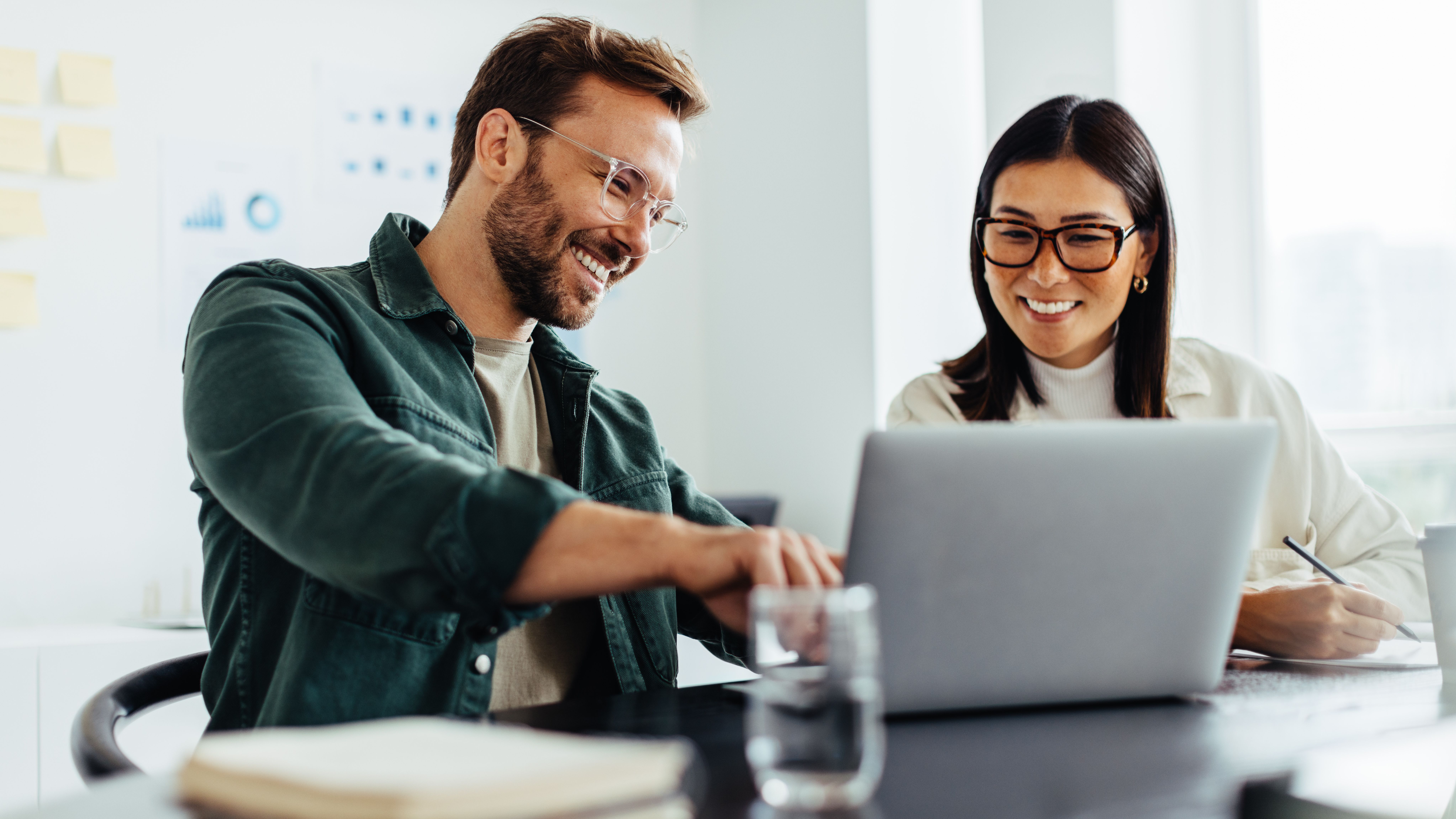 A man and a woman discussing something while pointing at a laptop.