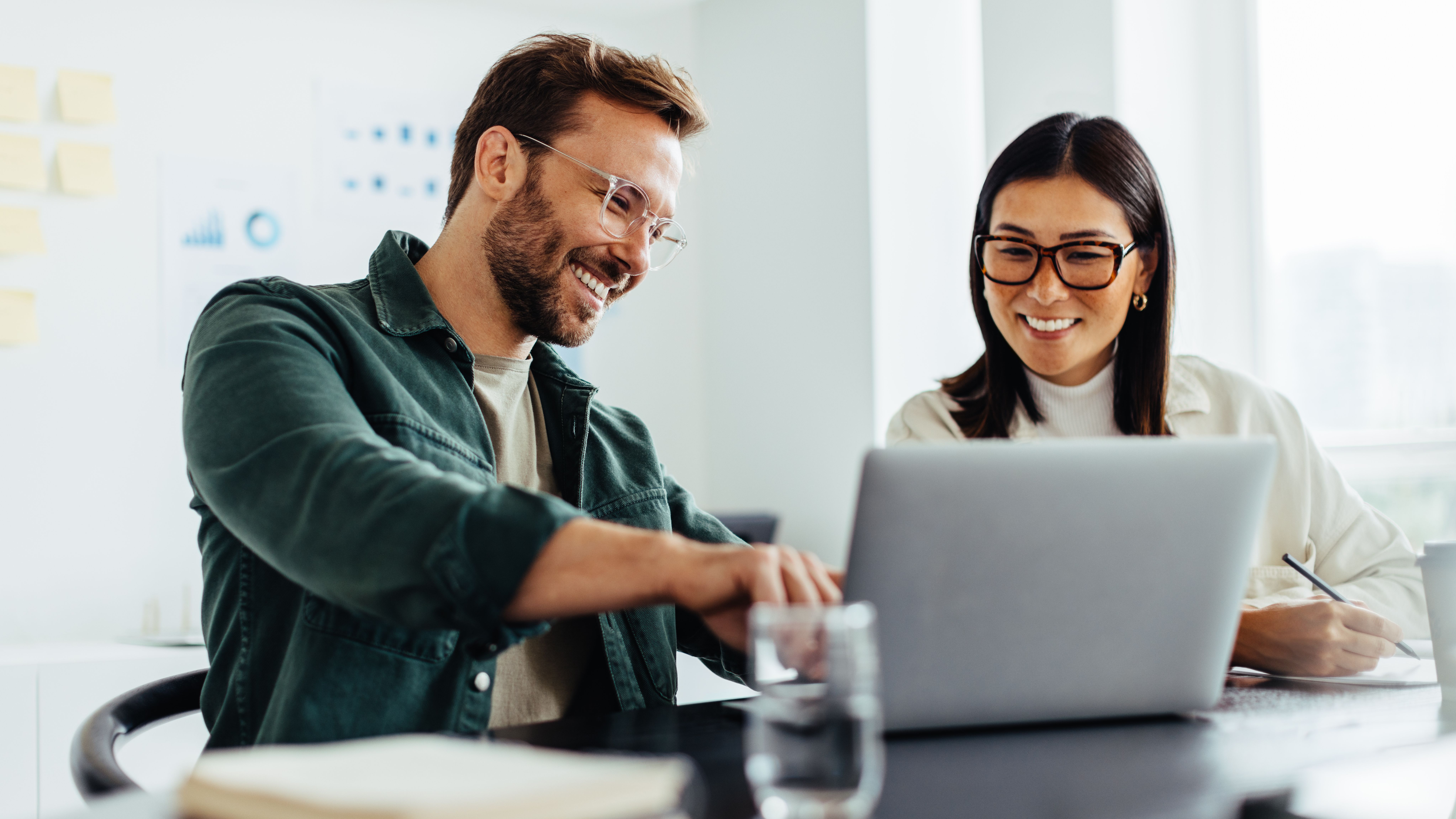 Mann und Frau besprechen etwas und zeigen dabei auf Laptop