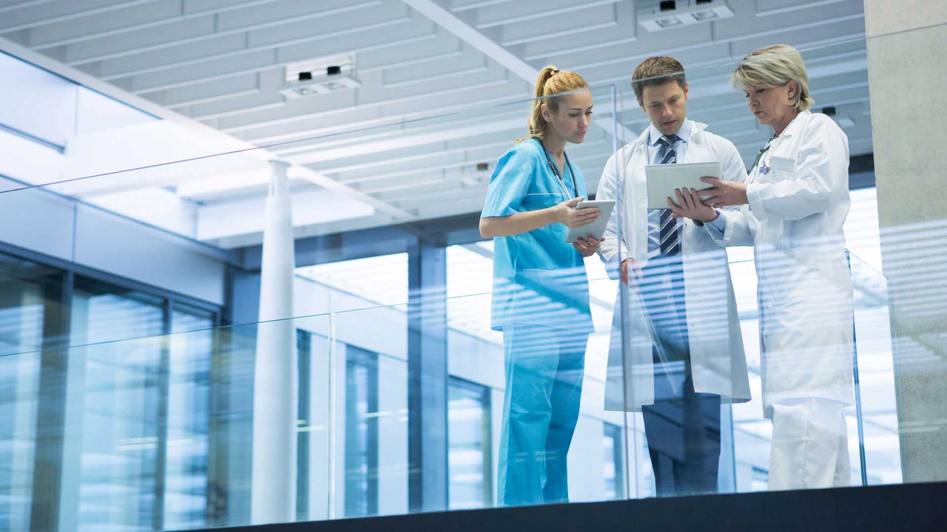 Three people in scrucs in discussion in a hospital