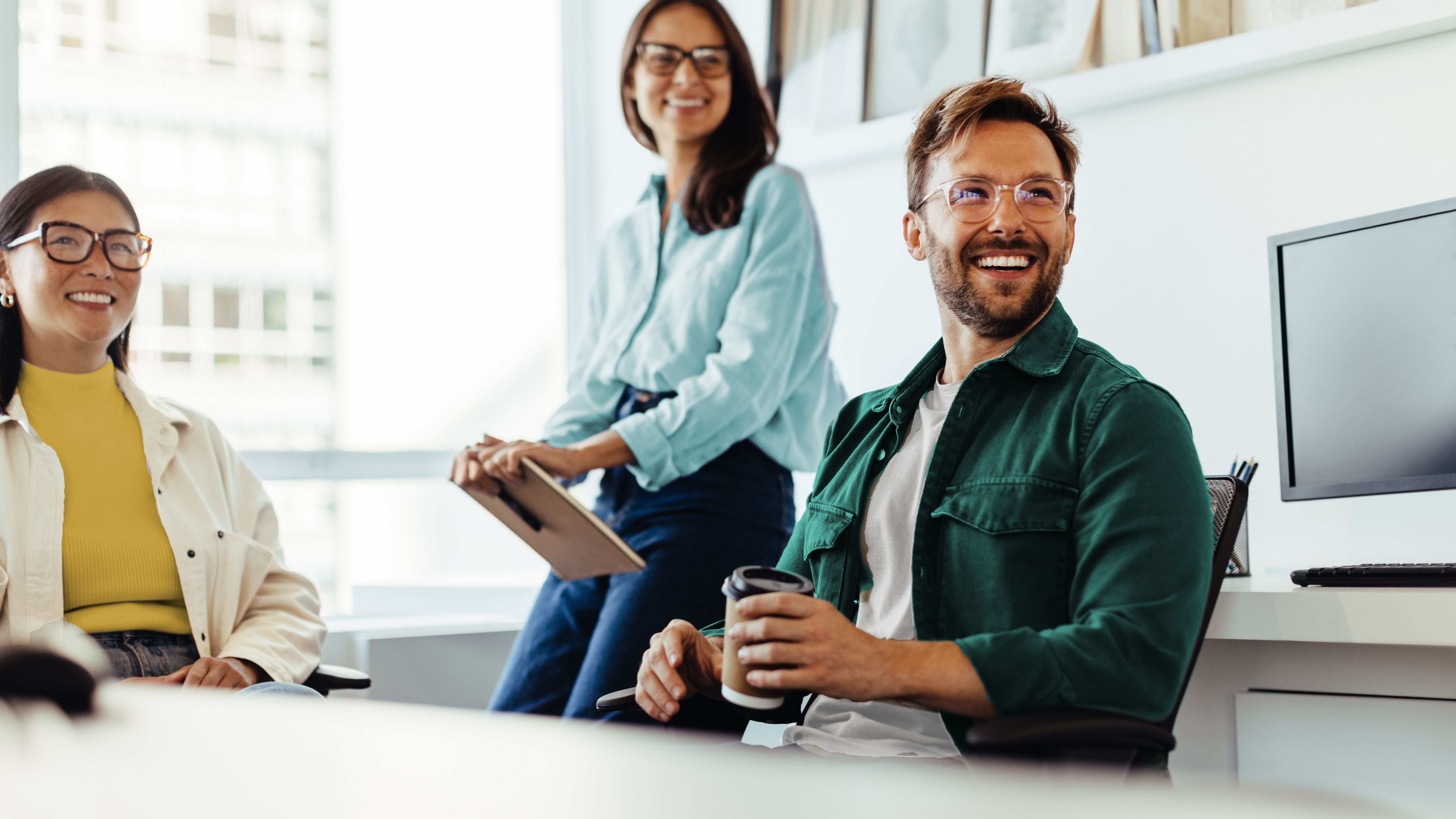 Zwei Frauen und ein Mann lachend im Office