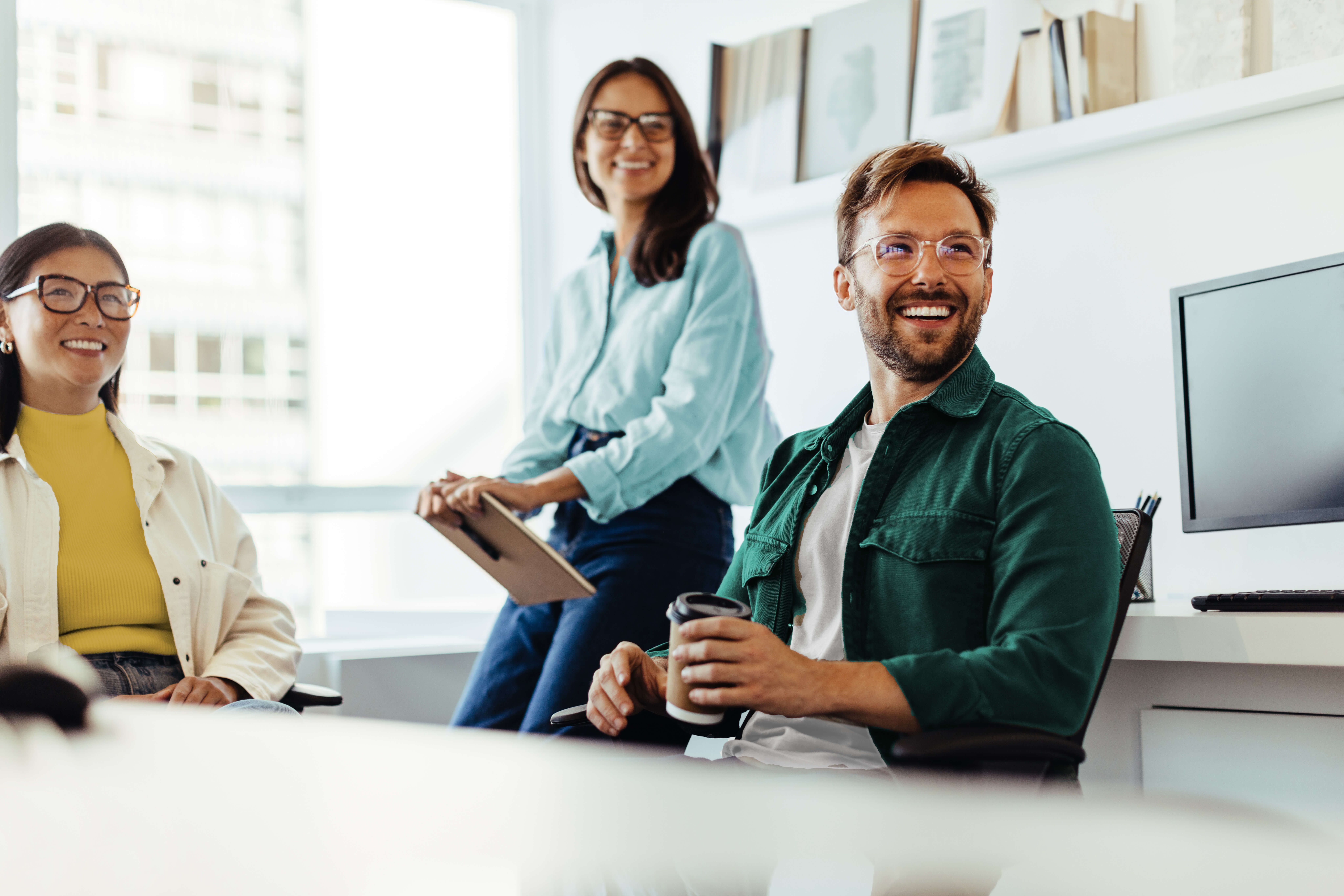 Zwei Frauen und ein Mann lachend im Office