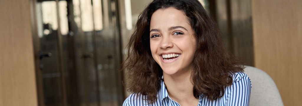 Lachendes, sitzendes Mädchen mit Mobile in der Hand